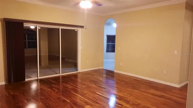 a view of an empty room with wooden floor and a window