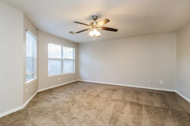 an empty room with a ceiling fan and a window