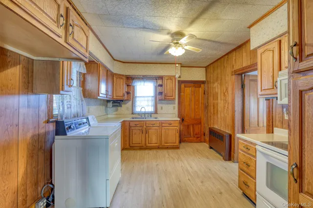 a kitchen with stainless steel appliances granite countertop a refrigerator a sink dishwasher a stove and white cabinets with wooden floor