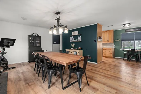 a kitchen with stainless steel appliances granite countertop a refrigerator a stove a sink a dining table and chairs with wooden floor