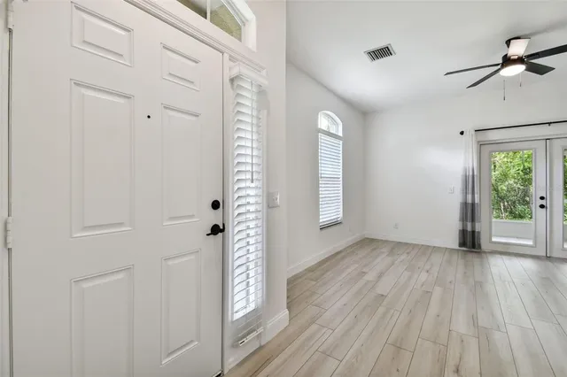 an empty room with wooden floor fan and windows