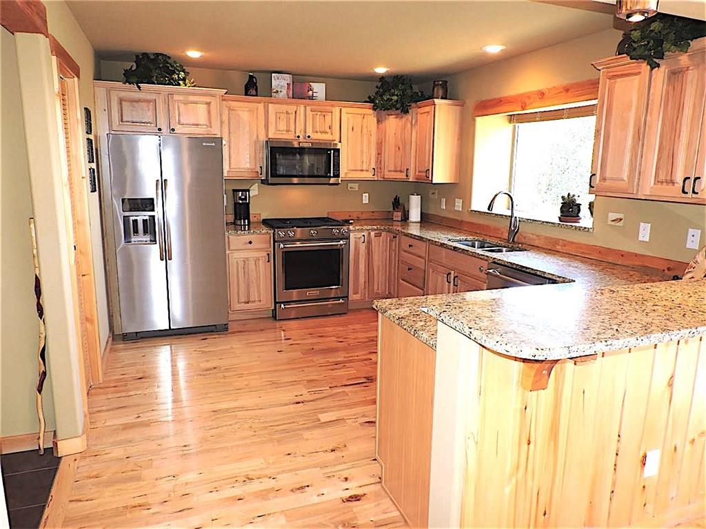299 Gadwall Road Como, CO 80432 - Photo 6 of 25 a kitchen with stainless steel appliances granite countertop a refrigerator a stove and a sink with wooden floor