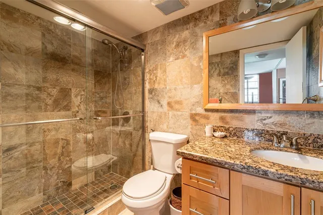 a bathroom with a granite countertop sink a toilet and shower