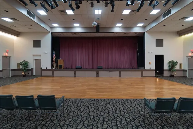 a room with lots of tables a large window and chairs