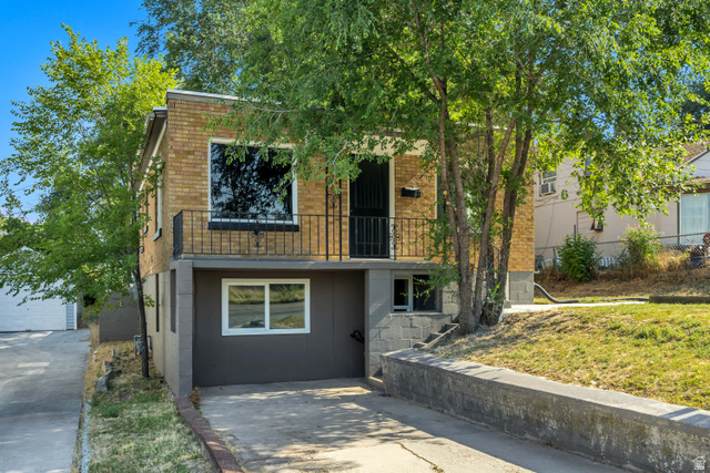 662 29th Street Ogden, UT 84403 - Photo 19 of 23 Brick facade residence featuring a balcony with iron railing, lower-level windows, and a paved driveway