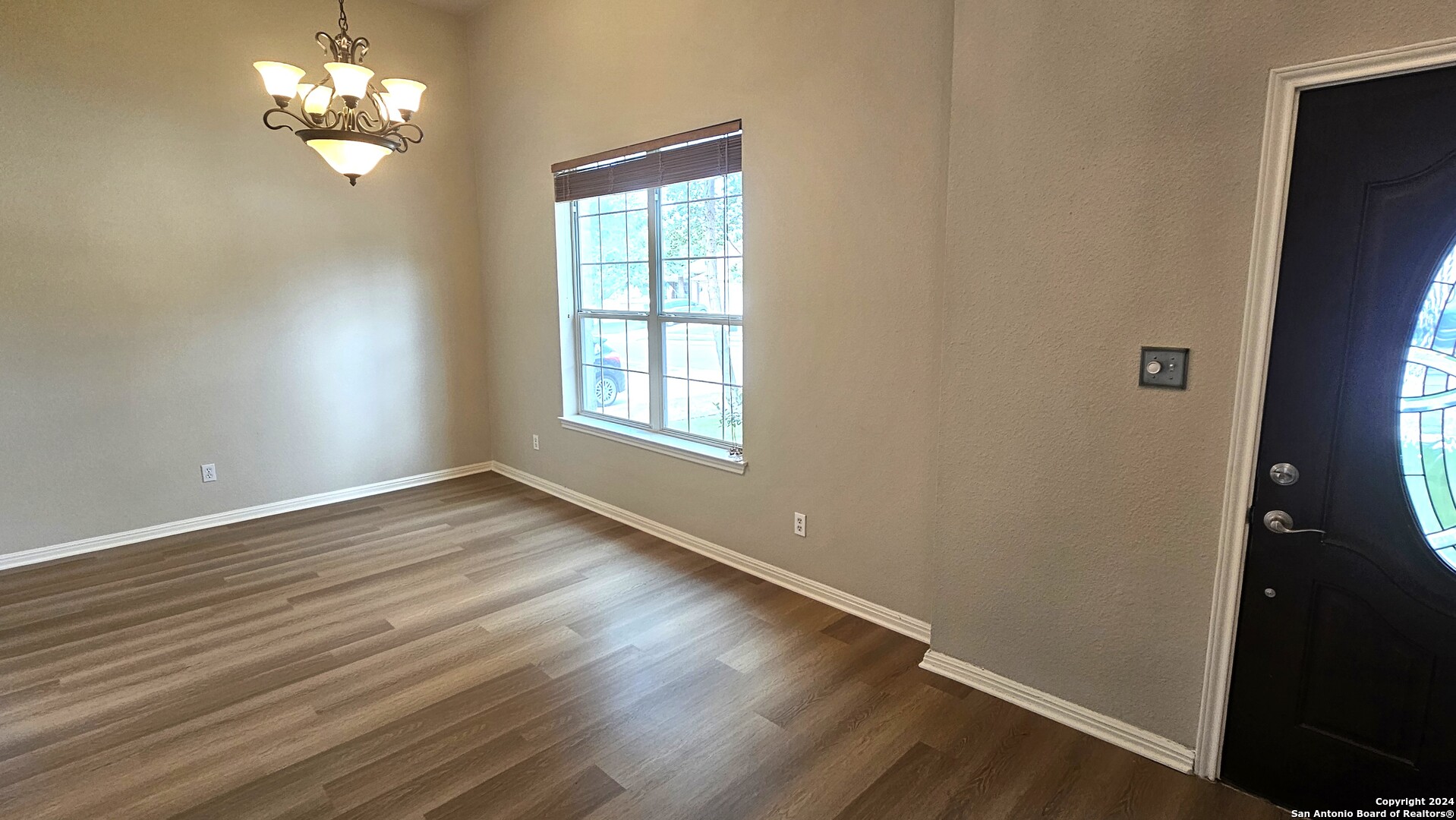 209 Storm Mt Road Cibolo, TX 78108 - Photo 11 of 28 an empty room with wooden floor chandelier fan and windows