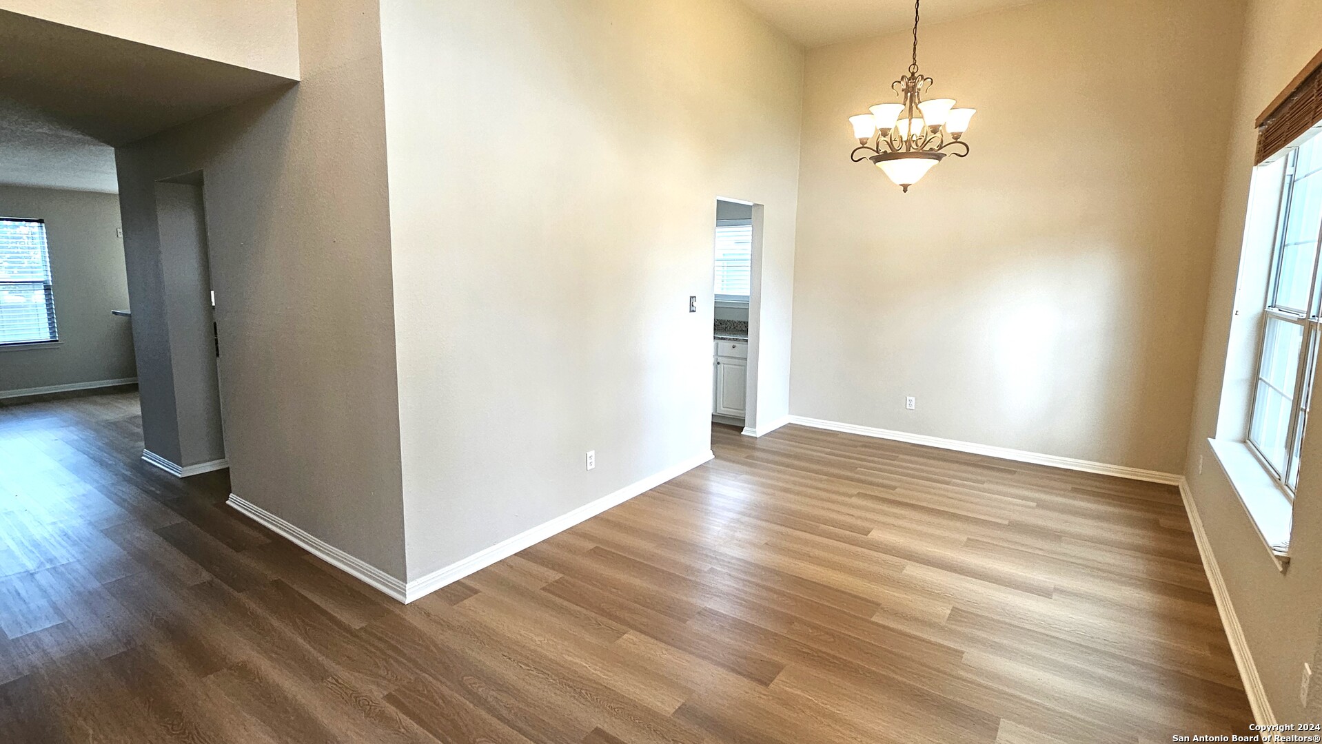 209 Storm Mt Road Cibolo, TX 78108 - Photo 13 of 28 an empty room with wooden floor chandelier and windows