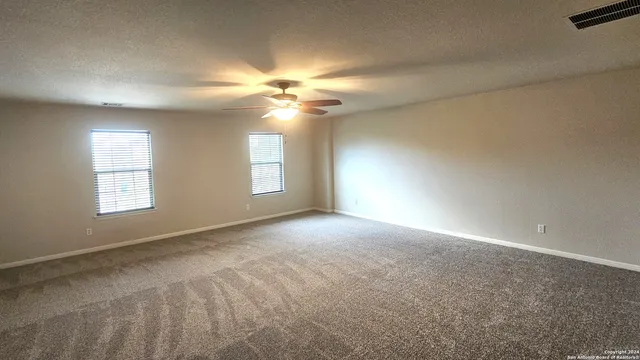 an empty room with windows and ceiling fan