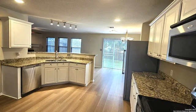 a kitchen with stainless steel appliances granite countertop a stove a sink and a refrigerator