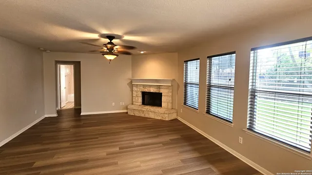 a view of an empty room with a window and wooden floor
