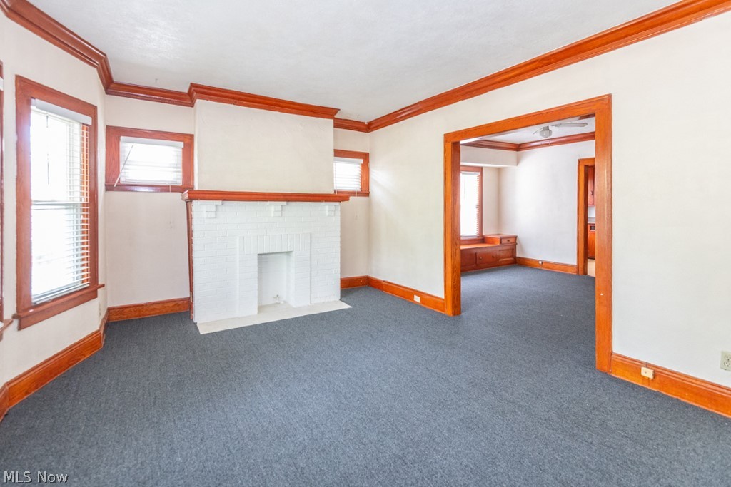 917 Helmsdale Road Cleveland Heights, OH 44112 - Photo 5 of 28 Unfurnished living room with carpet flooring, healthy amount of natural light, ornamental molding, and a fireplace