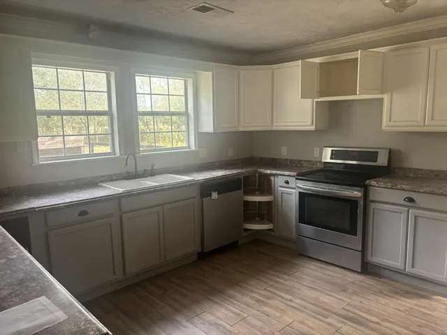 a kitchen with cabinets appliances a sink and a window