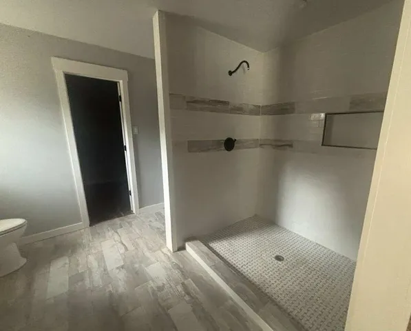 an empty room with wooden floor ceiling fan and windows