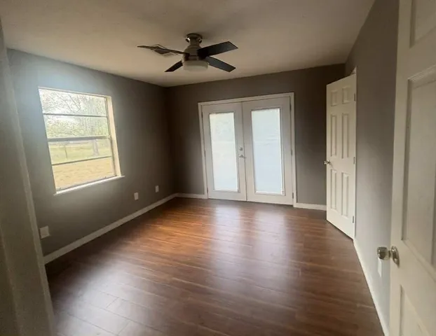 an empty room with wooden floor and windows