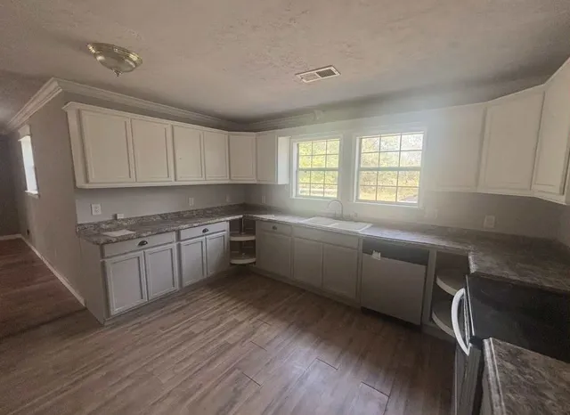 a kitchen with granite countertop a sink cabinets stainless steel appliances and window