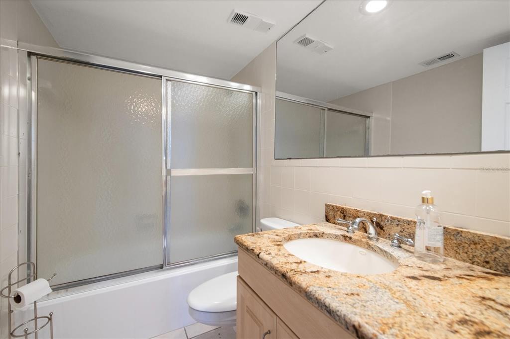 18201 Gulf Boulevard, Unit 401 Redington Shores, FL 33708 - Photo 29 of 42 a bathroom with a granite countertop sink toilet and shower