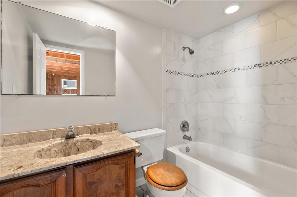 18201 Gulf Boulevard, Unit 401 Redington Shores, FL 33708 - Photo 35 of 42 a bathroom with a granite countertop sink a toilet and bathtub