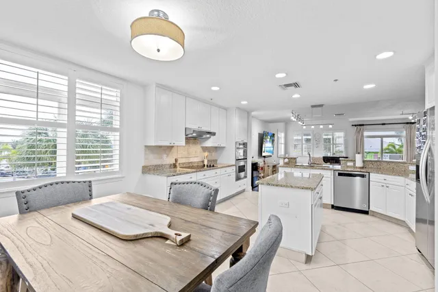 a large kitchen with kitchen island a large counter space a sink appliances and a view of living room