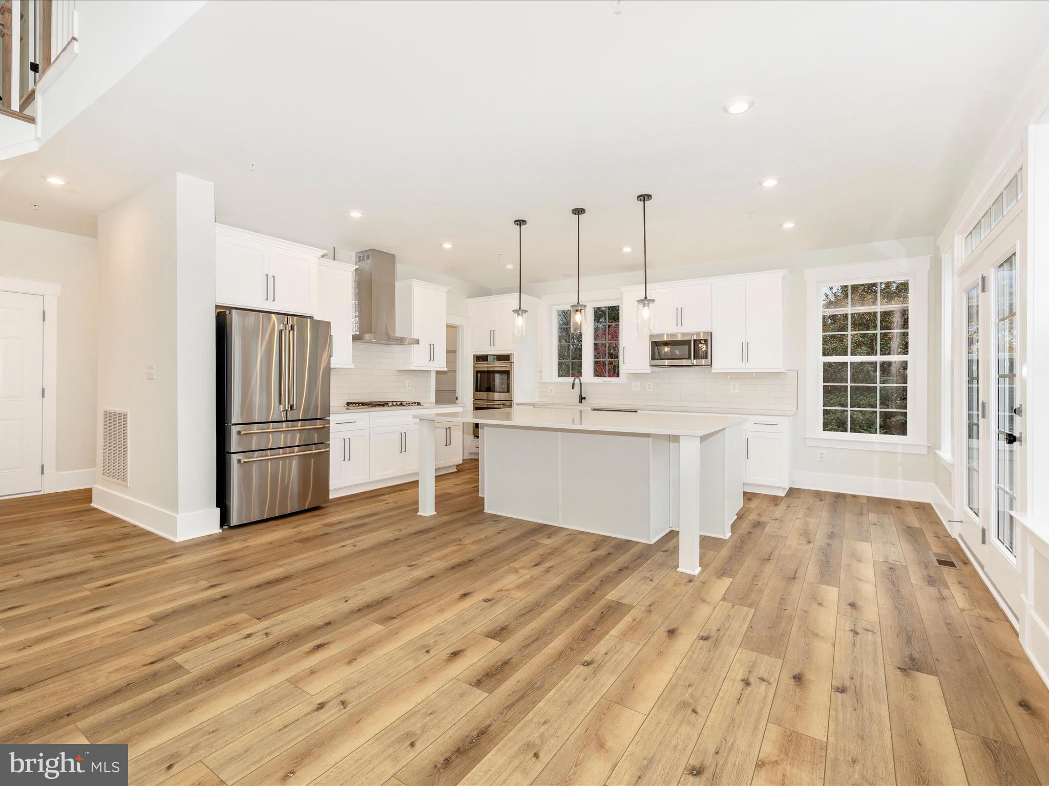 7022 Ridge Road Frederick, MD 21702 - Photo 15 of 63 a large white kitchen with stainless steel appliances kitchen island granite countertop a stove a sink dishwasher and a refrigerator with wooden floor