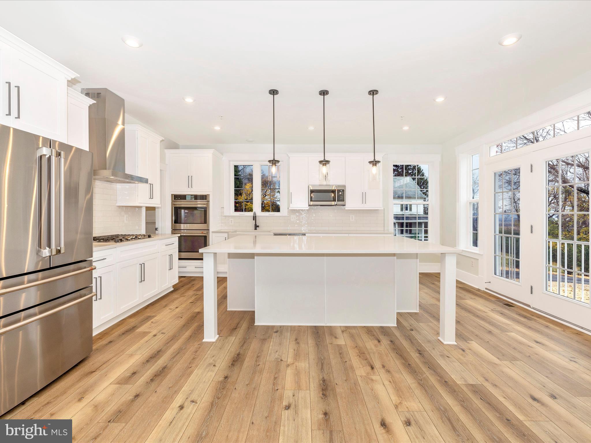 7022 Ridge Road Frederick, MD 21702 - Photo 19 of 63 a large white kitchen with kitchen island a stove a refrigerator cabinets and wooden floor