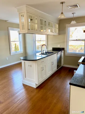 a kitchen with stainless steel appliances granite countertop a sink a stove cabinets and wooden floor