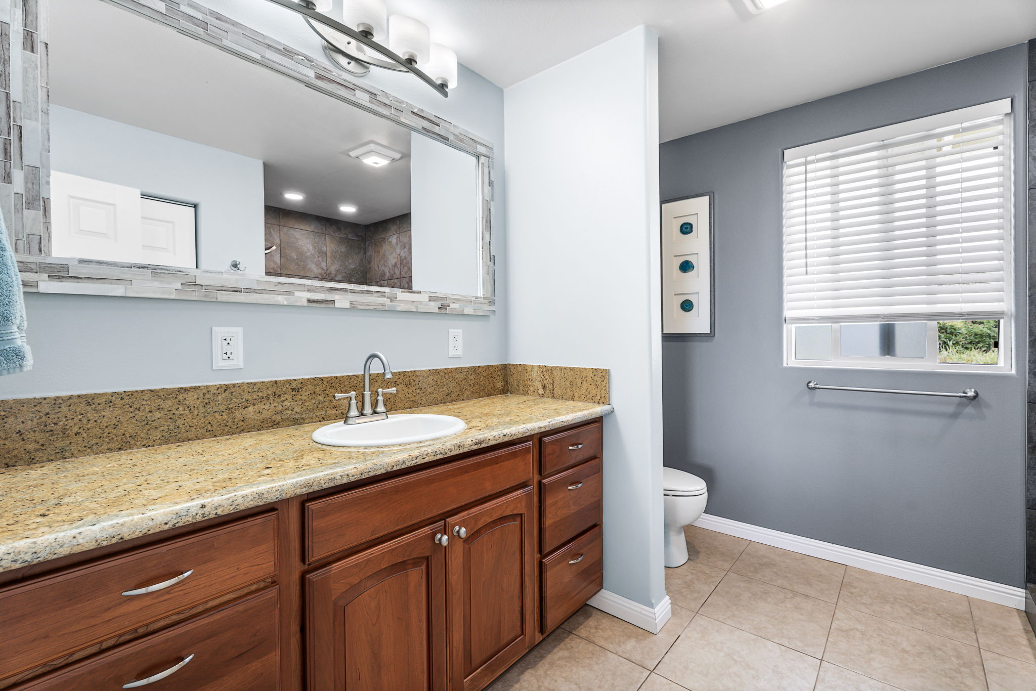 94-6494 Keoki Road Naalehu, HI 96772 - Photo 11 of 30 a bathroom with a granite countertop sink a toilet and a mirror