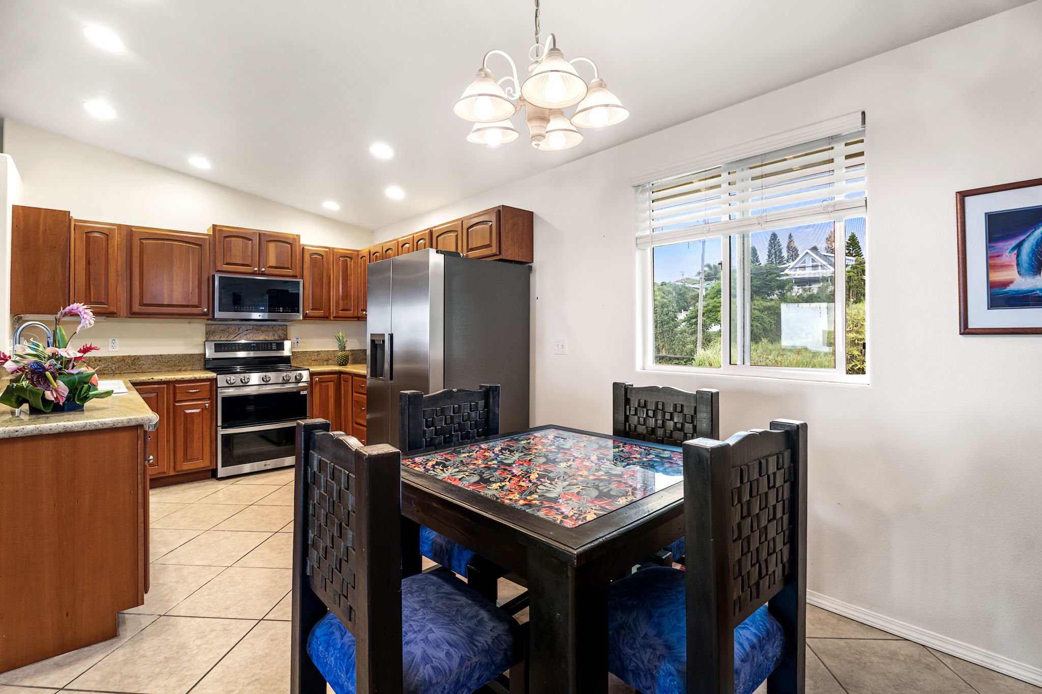 94-6494 Keoki Road Naalehu, HI 96772 - Photo 8 of 30 a kitchen with stainless steel appliances granite countertop a refrigerator a stove top oven a sink dishwasher a dining table and chairs