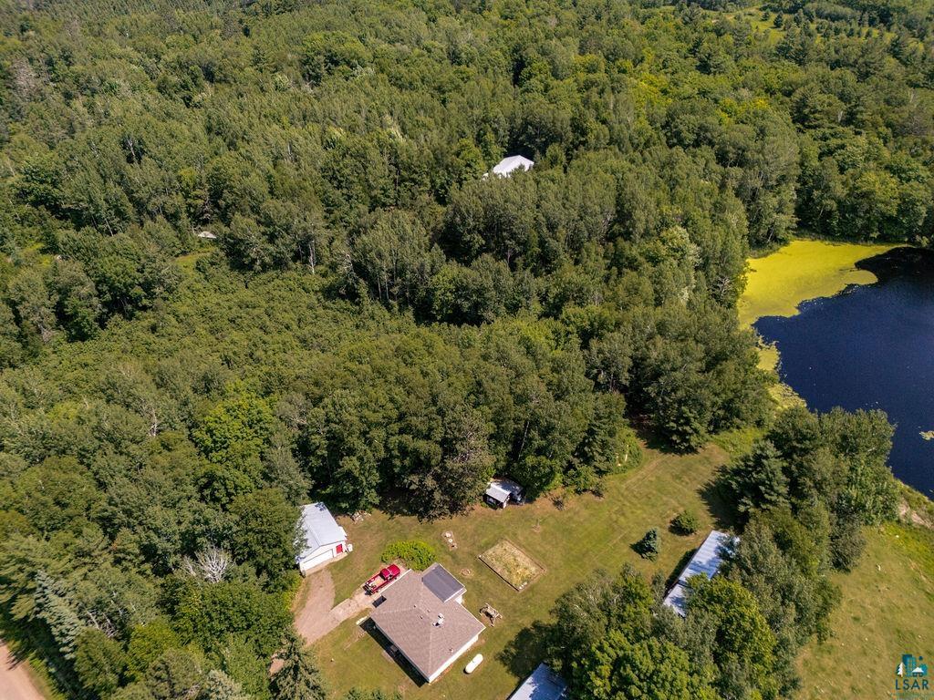 2592 Strandberg Road Barnum, MN 55707 - Photo 43 of 44 Expansive wooded acreage featuring a main residence with a brown shingle roof, multiple outbuildings, and a private pond