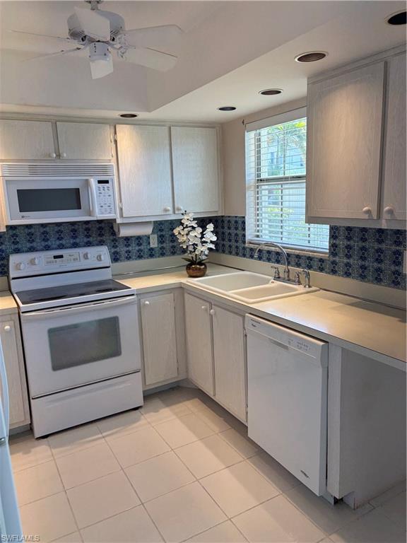 315 St Andrews Boulevard, Unit A2 Naples, FL 34113 - Photo 12 of 17 Kitchen featuring white appliances, light countertops, a ceiling fan, light tile patterned floors, and white cabinets