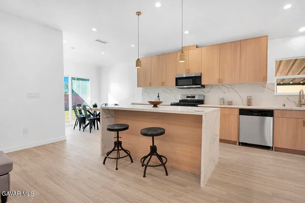 a kitchen with stainless steel appliances granite countertop a stove a sink a microwave a island with a dining table and chair