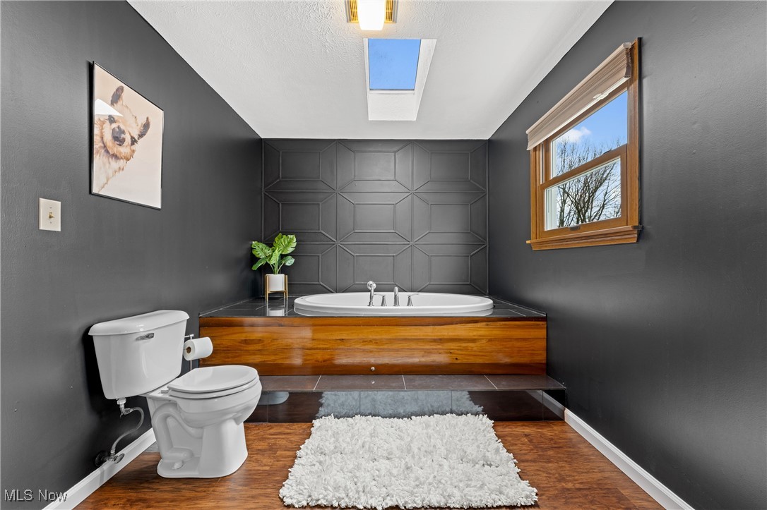 645 Killinger Road Clinton, OH 44216 - Photo 33 of 50 Bathroom with wood-type flooring, a skylight, toilet, and a tub