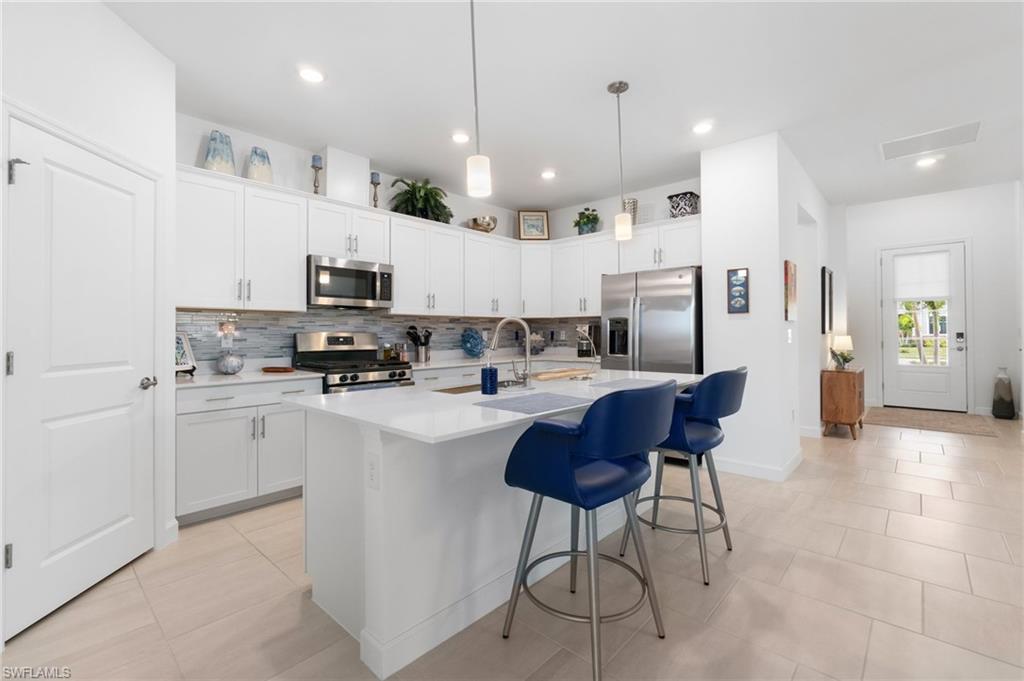 20238 Millrun Drive Estero, FL 33928 - Photo 14 of 41 a kitchen with stainless steel appliances kitchen island granite countertop a sink a stove a refrigerator and chairs