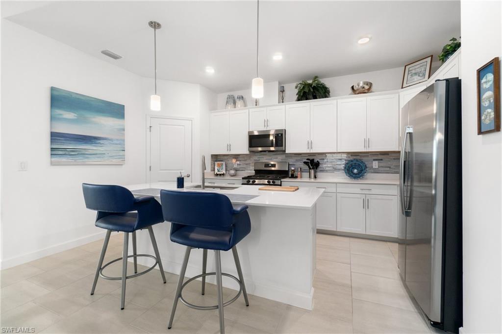 20238 Millrun Drive Estero, FL 33928 - Photo 16 of 41 a kitchen with stainless steel appliances kitchen island granite countertop a refrigerator and a stove top oven with white cabinets