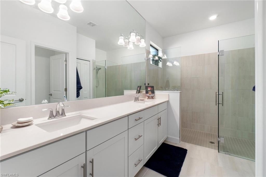 20238 Millrun Drive Estero, FL 33928 - Photo 20 of 41 a bathroom with a double vanity sink a large mirror and shower