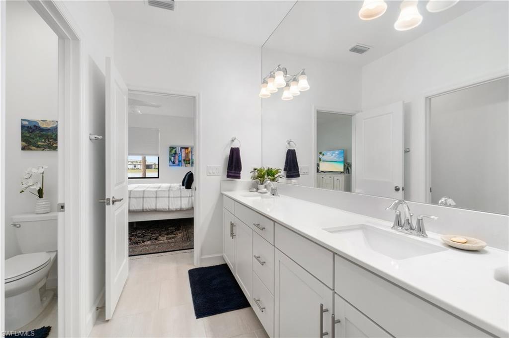 20238 Millrun Drive Estero, FL 33928 - Photo 21 of 41 a spacious bathroom with a double vanity sink a mirror and a toilet