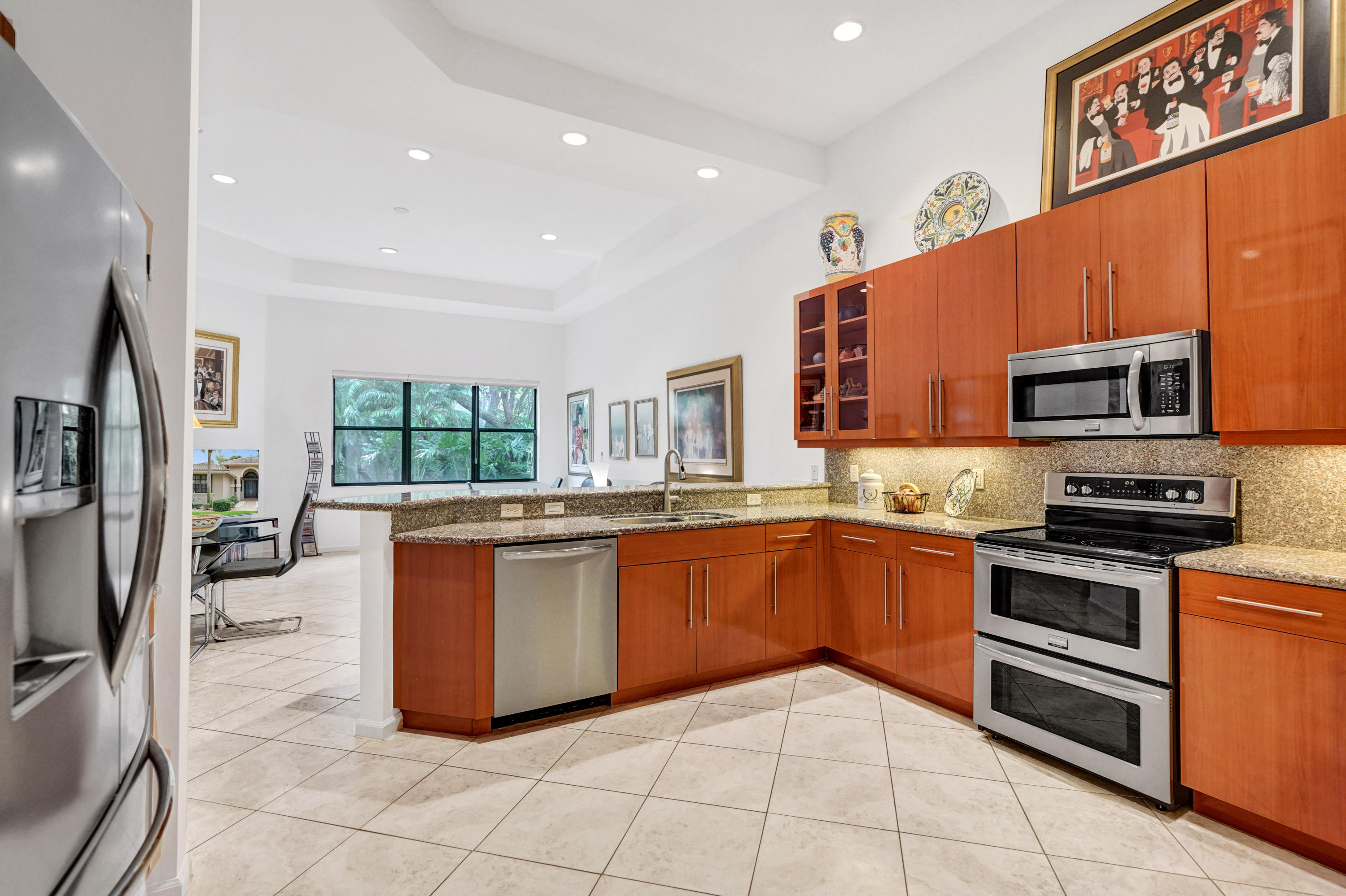 7849 Via Grande Boynton Beach, FL 33437 - Photo 29 of 59 a large kitchen with stainless steel appliances granite countertop a stove top oven a sink dishwasher a dining table and chairs with wooden floor