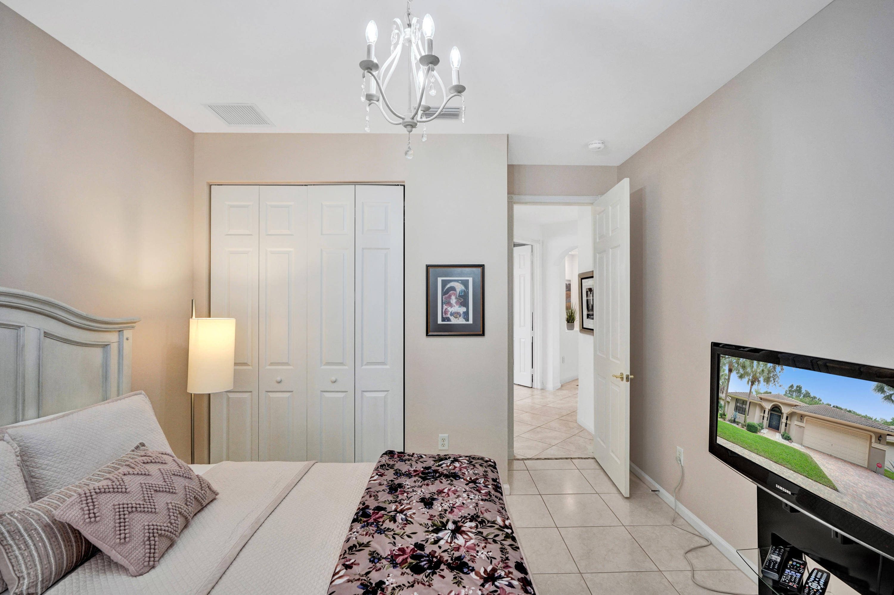 7849 Via Grande Boynton Beach, FL 33437 - Photo 39 of 59 a bedroom with a bed and a chandelier