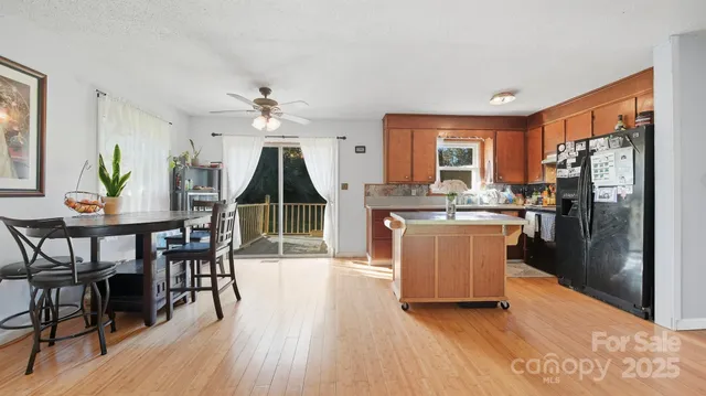 a kitchen with stainless steel appliances granite countertop a table chairs and a refrigerator