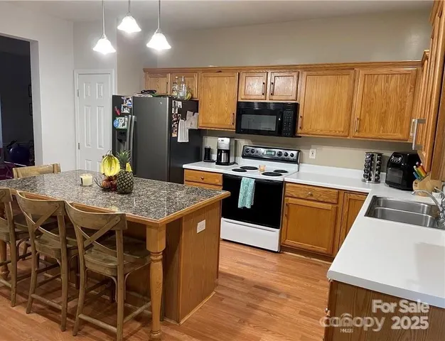 a kitchen with stainless steel appliances granite countertop a stove top oven a sink refrigerator and cabinets