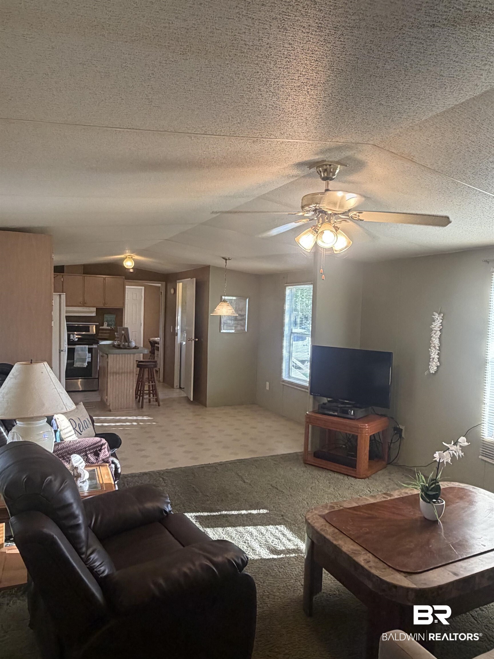 1125 Ridgewood Drive Lillian, AL 36549 - Photo 3 of 36 Open-concept living area featuring a ceiling fan with integrated lighting, textured ceilings, and a light green wall finish