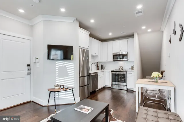 a kitchen with stainless steel appliances sink refrigerator dining table and chairs