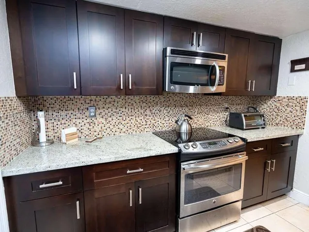 a kitchen with granite countertop stainless steel appliances a stove sink and microwave