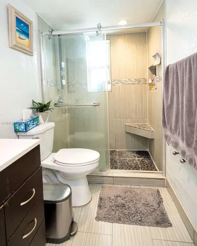 a bathroom with a granite countertop toilet a sink and a shower