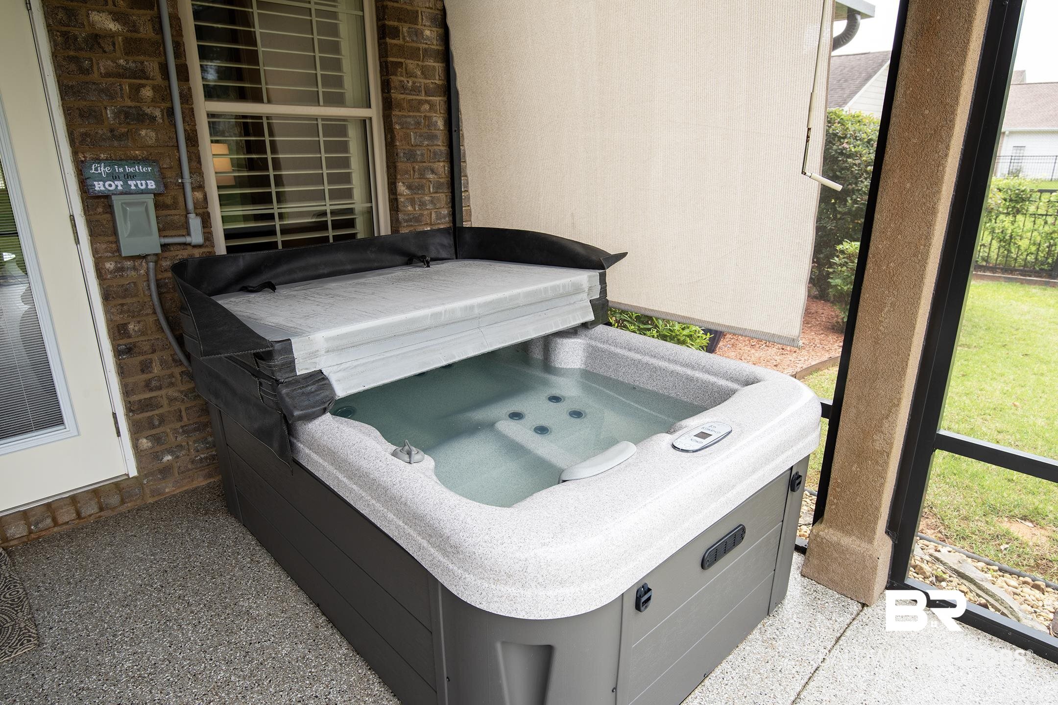 9357 Lakeview Drive Foley, AL 36535 - Photo 24 of 68 Integrated outdoor spa with a partially retracted cover, situated on a textured composite patio