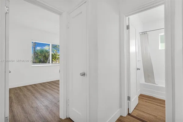 a view of a hallway with wooden floor and a bathroom