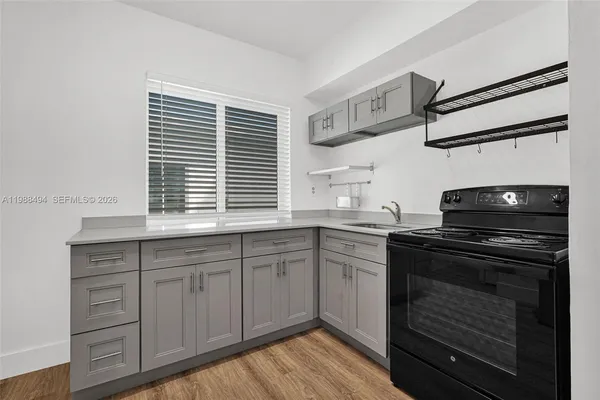 a kitchen with cabinets wooden floor and a stove top oven