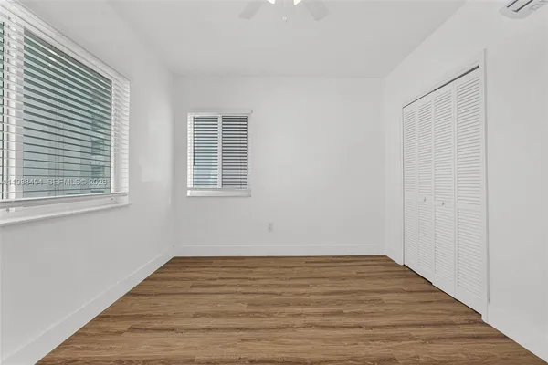 a view of empty room with wooden floor and fan