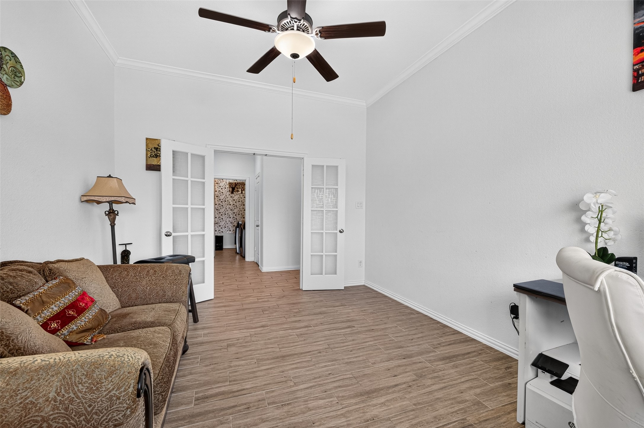 A second view reveals just how adaptable this space can be, with room for both productivity and relaxation. The high ceiling, glass french doors and generous footprint keep the room feeling open rather than confined.