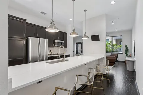 a kitchen with stainless steel appliances a dining table chairs refrigerator and microwave
