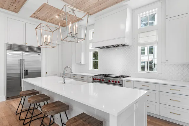 a large white kitchen with a large window and stainless steel appliances